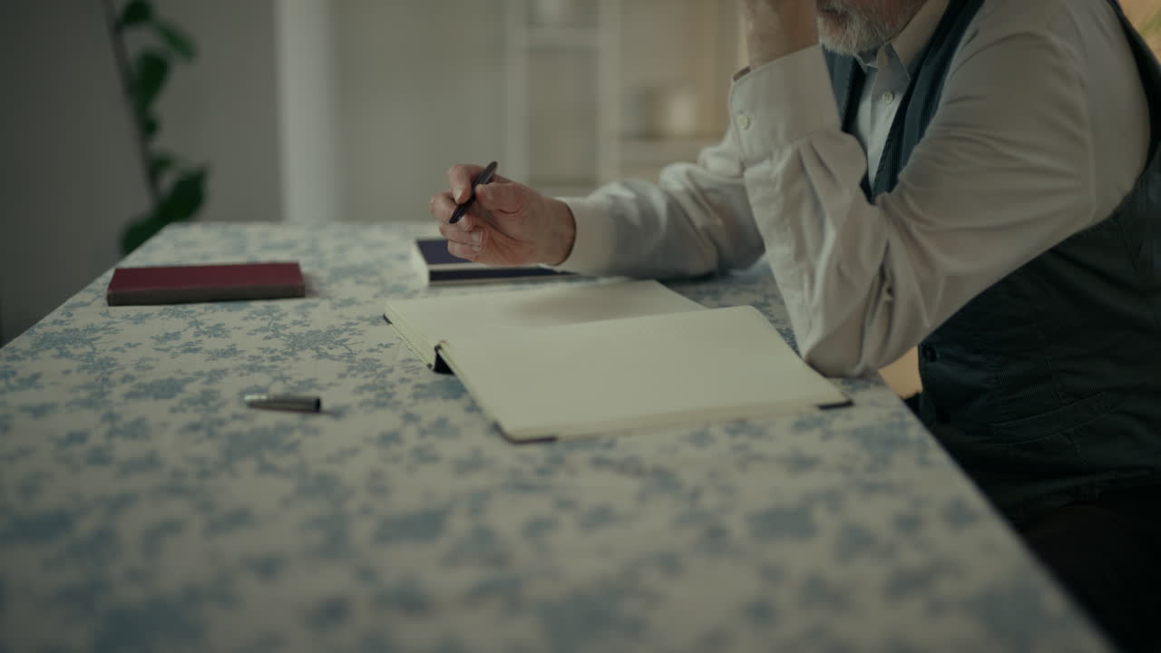 Man Writing in a Notebook at a Table