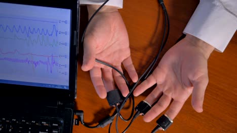 las manos del hombre conectadas al circuito del detector de mentiras.