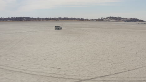 4x4 car driving on dry salt pan of makgadikgadi towards kubu island in botswana, south africa