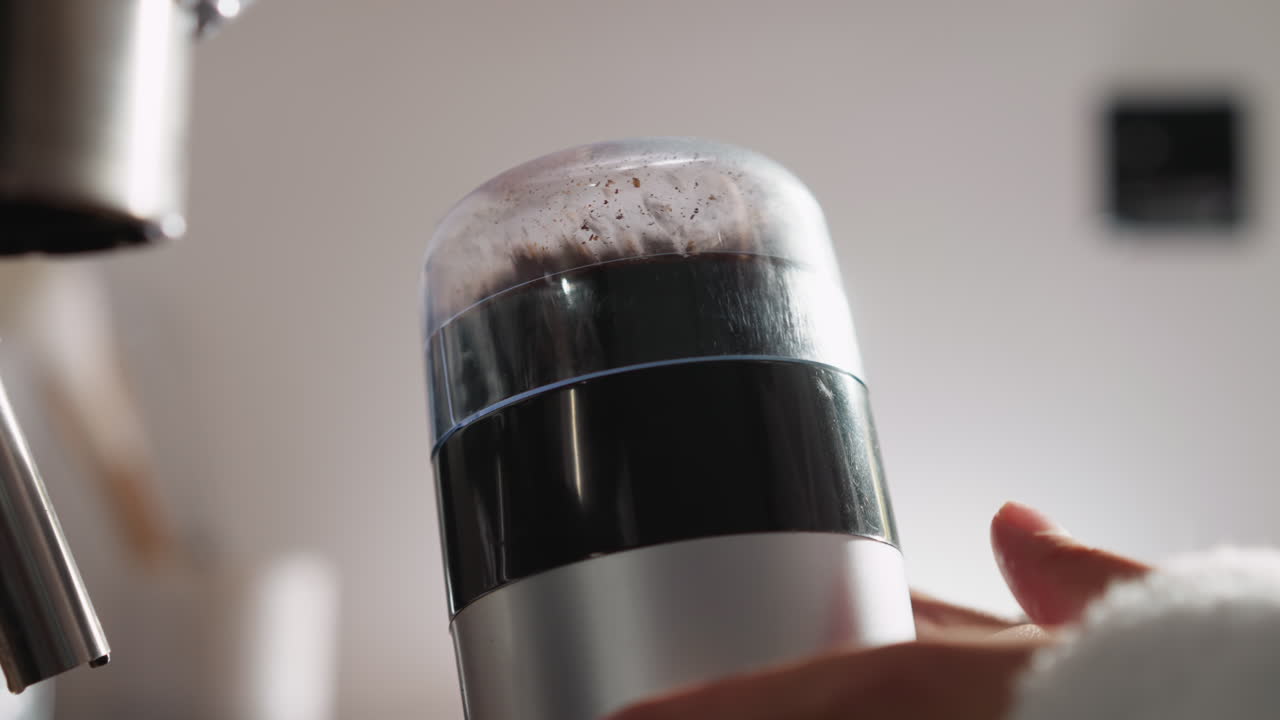 부인이 커피 콩을 는 기기 클로즈업. 은 옷을 입은 여자가 주방 기기로 곡물을 는. 맛있는 카페인 음료를 만드는 과정