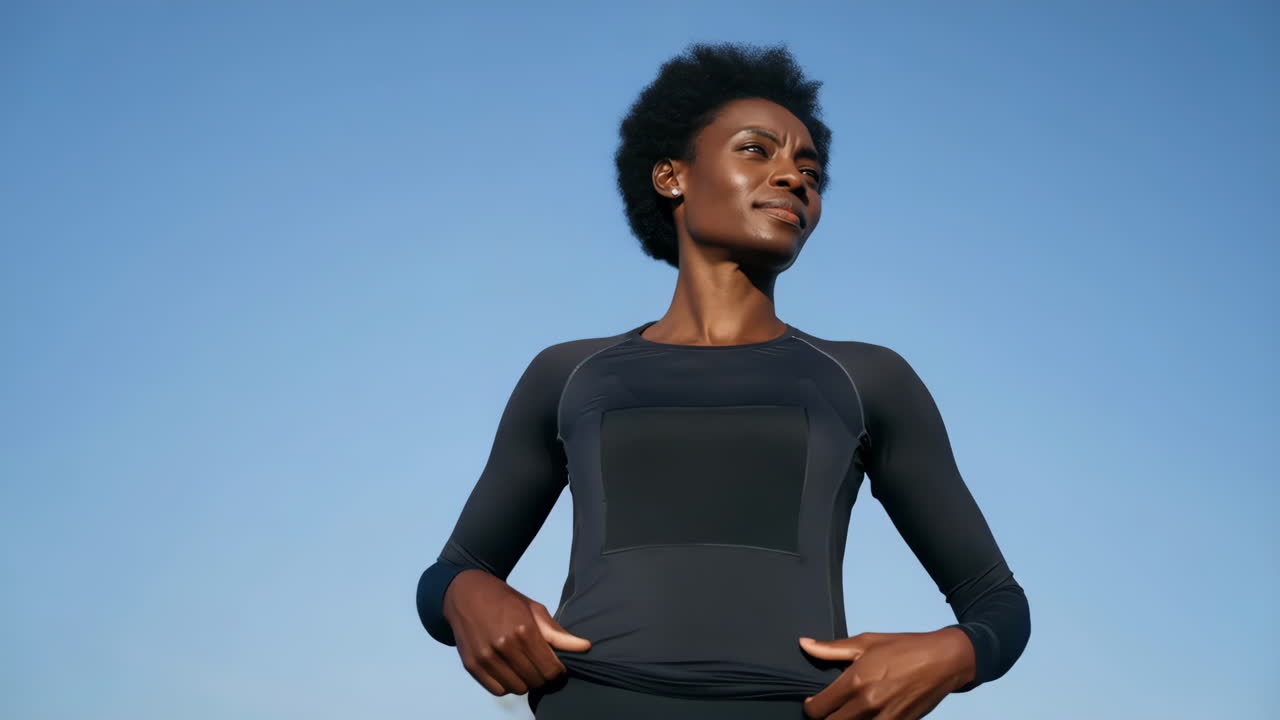 Afro-Amerikaanse vrouwelijke atleet poseert tegen blauwe lucht