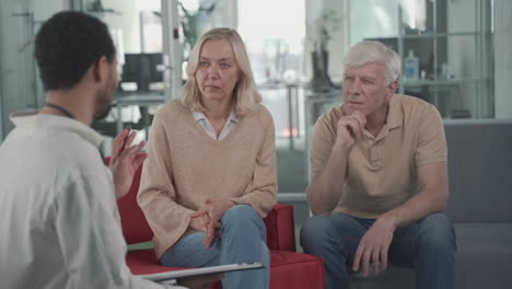 una pareja de ancianos escucha atentamente a un joven médico negro 1