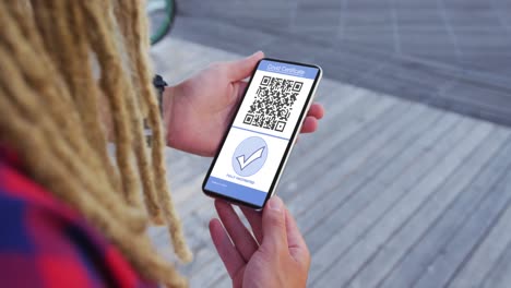 Man-with-dreadlocks-holding-smartphone,-covid-vaccination-certificate-and-qr-code-on-screen