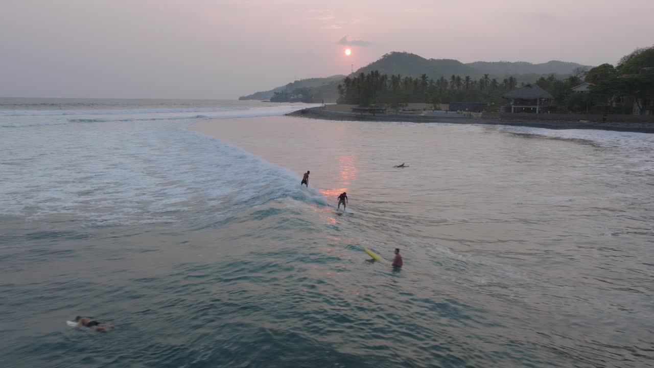 해가 지는 동안 파도를 공유하는 두 명의 서퍼 엘  ⁇ 코 엘 살바도르
