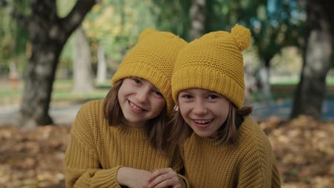 portrait of child siblings standing in the woods and wearing yellow hats.