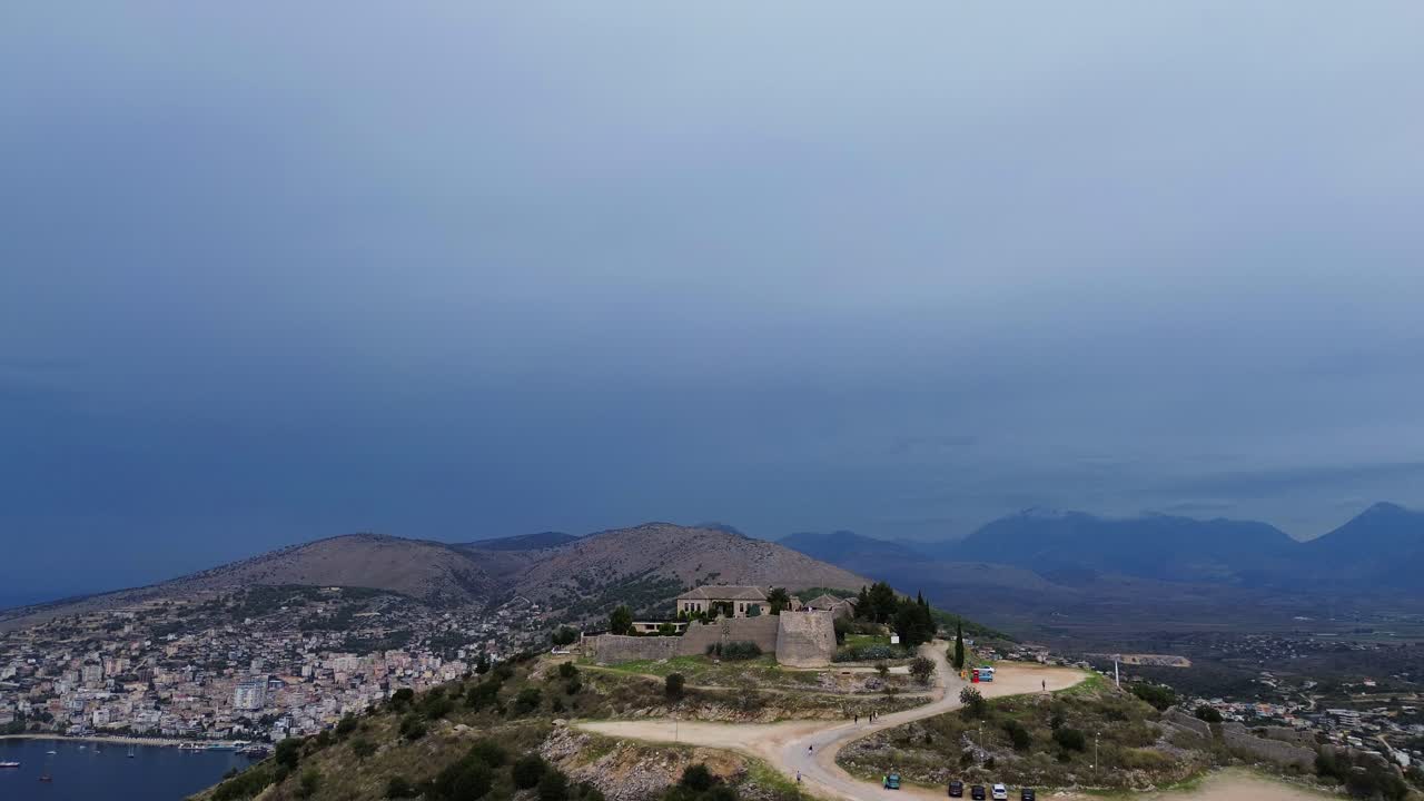 Veduta aerea di un castello su una collina che domina una città e il mare