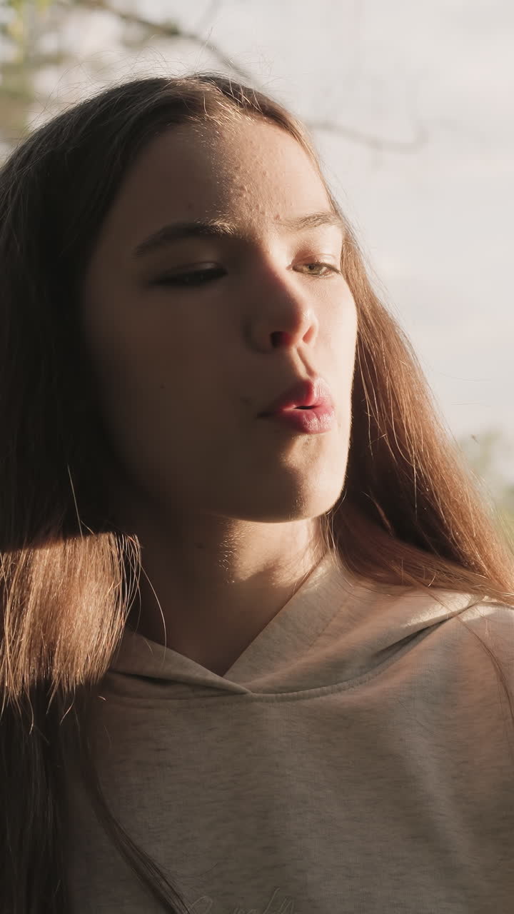 mujer toca el tronco de un árbol en el bosque. la luz del sol cae sobre la joven soplando la pelusa voladora. amor y reverencia por la naturaleza salvaje en un clima soleado