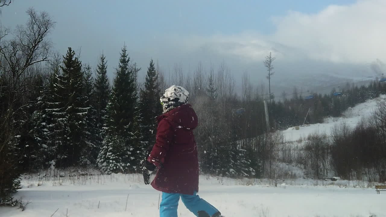 ребенок бросает снежный шар в белое поле во время падения хлопьев, через плечо