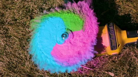 colorful pink, green and blur chalk powder on an angle grinder or a disk grinder spinning and and forming a cloud in slow motion while the angle grinder starts spinning fast