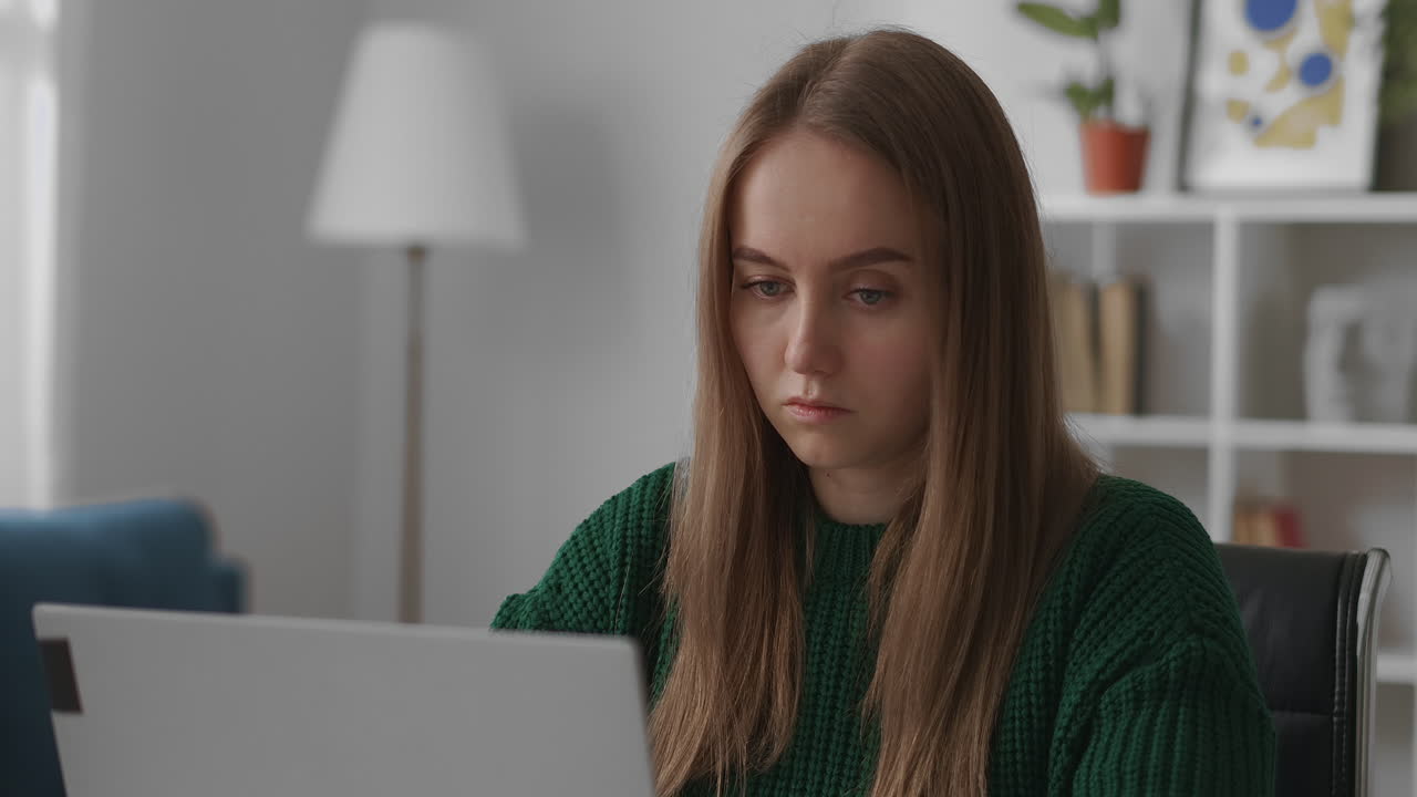 una estudiante está aprendiendo en línea frente a una computadora portátil sentada en un apartamento educación remota durante el aislamiento en la pandemia retrato en primer plano de una mujer