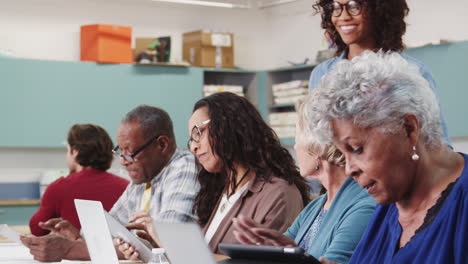 Senior-Female-Student-Raising-Hand-To-Ask-Question-In-IT-Class-In-Community-Centre-With-Teacher