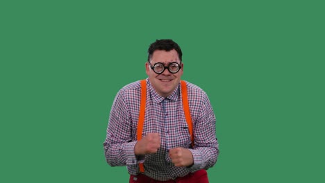 el hombre, encorvado, baila y canta junto a las melodías. un hombre con gafas con lentes gruesas, en una camisa a cuadros con tirantes naranjas en el estudio en una pantalla verde. cámara lenta.