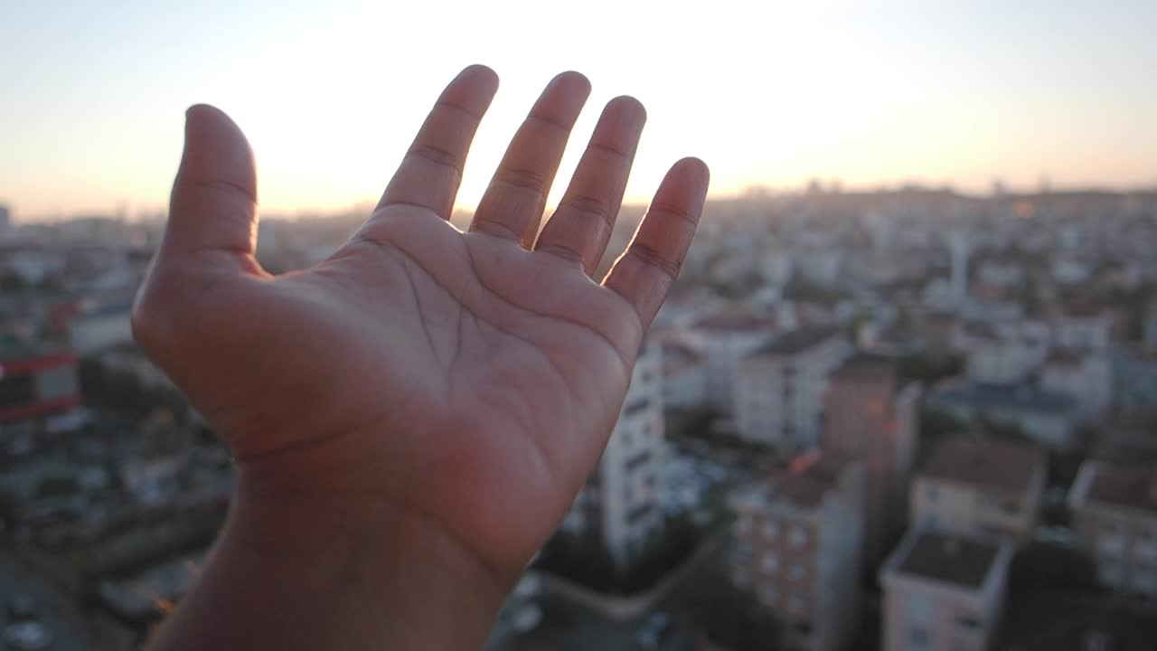 Hand Reaches Towards the City Sunset