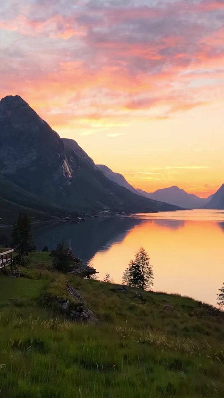 En fredfyldt solnedgang over stille vand: Naturens skønhed afsløret i et majestætisk landskab med bjerge, refleksioner og frodigt grønt.