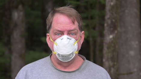 an adult man wearing n95 face mask to protect himself while in the forest in bandon, oregon - zoom-in shot