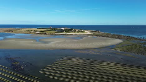 aerial drone footage of tatihou island in normandy on a sunny day, revealing its historic fort, green landscapes, and the vast oyster beds stretching across the glistening tidal flats