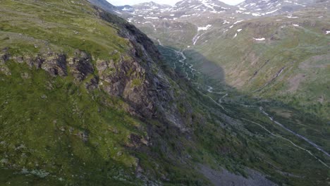 la cámara pasa por el costado de una montaña y revela el largo camino solitario estirado detrás de ella