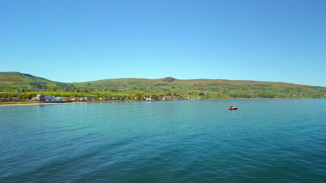 Aerial video of Ballygally on the Causeway Coastal Route on a bright and sunny day. The camera passes over the bay and onto the water. Filmed in Ballygally in 4K, 60FPS and with Rec800 color.