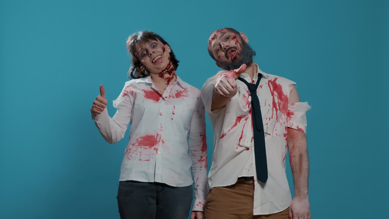 Approving evil looking zombies acting bizarre while giving thumbs up at camera on blue background