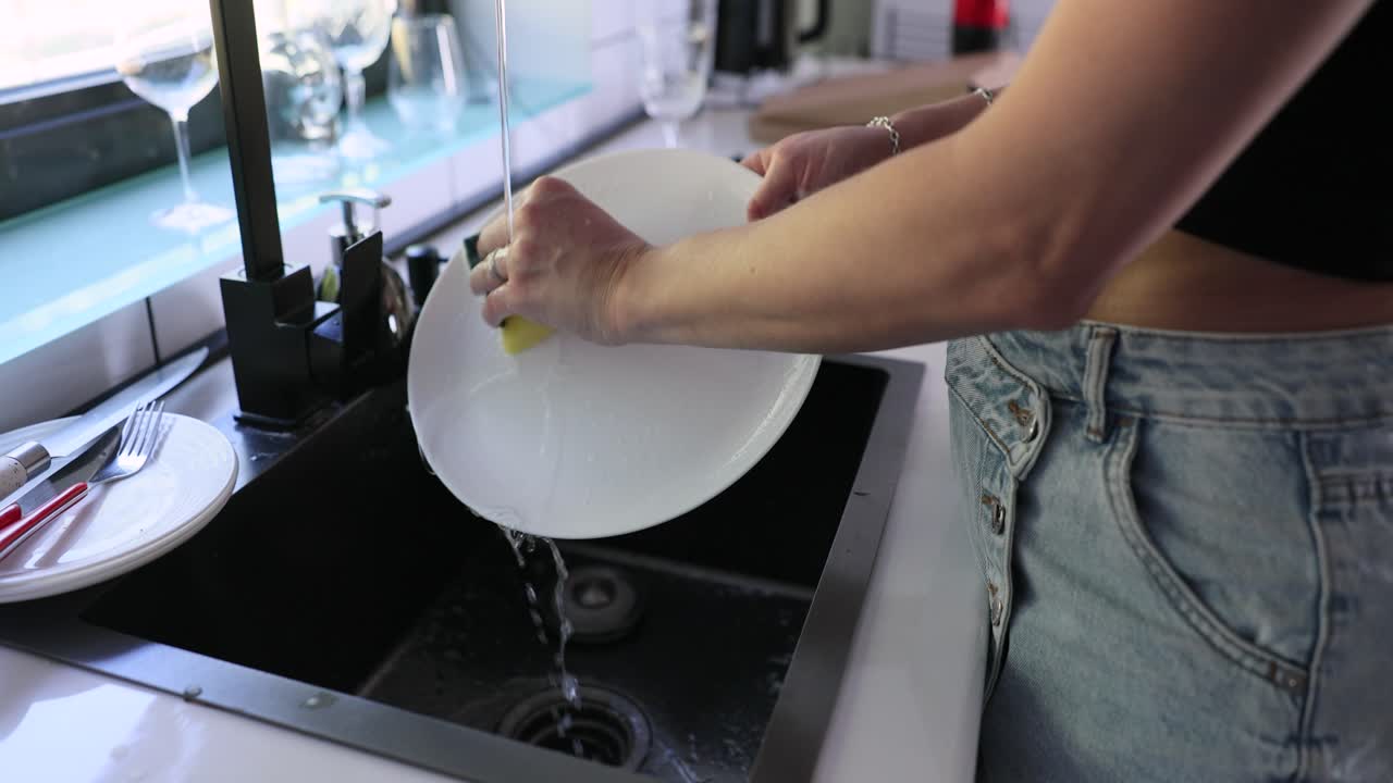 Mujer lavando platos en el fregadero de la cocina