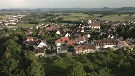 drone footage orbiting leftwards around aach village, focusing on the church tower and the historic town, while showcasing the surrounding landscape and village life.