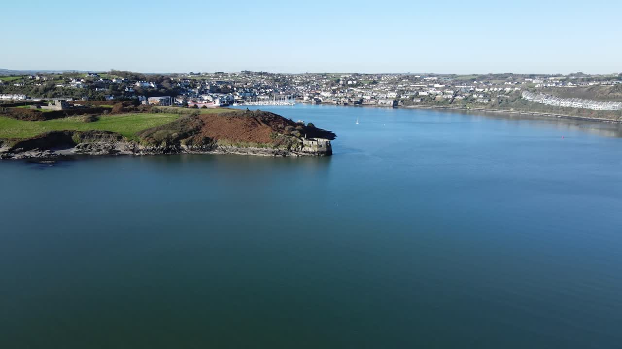 un panorama aéreo se desliza sobre el agua cerca del fuerte james y el puerto de kinsale en la distancia en un día soleado