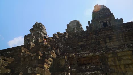 tourist woman climbing ta keo temple in angkor complex near siem reap, cambodia