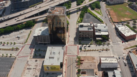 Aerial-view-of-various-buildings-along-highway.-Forward-flying-drone,-tilt-down-footage-of-multi-storey-commercial-property-with-glass-facade.-Dallas,-Texas,-US