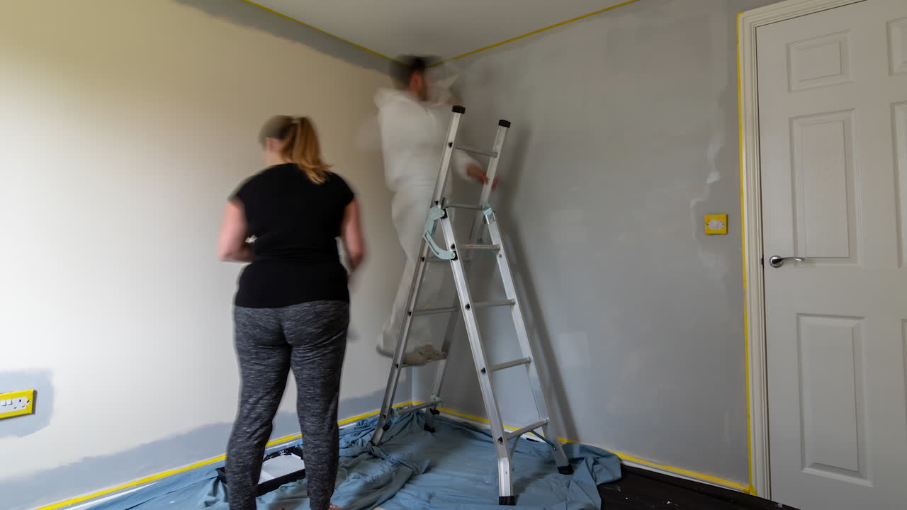 time-lapse with camera panning slowly right as couple redecorate and paint room together