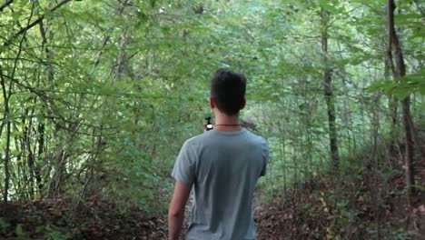 man walking in the green forest - shot from behind