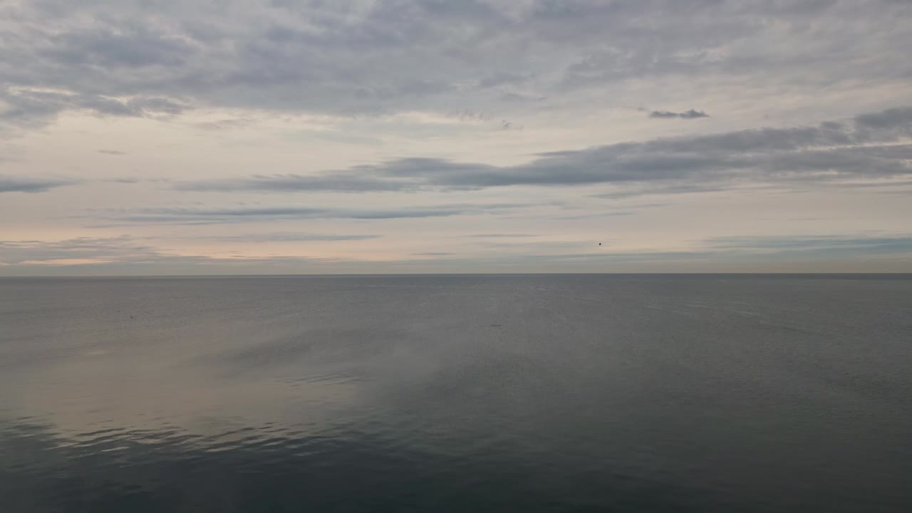 조용한 바다에 반사되는 구름이 가득한 일몰 하늘