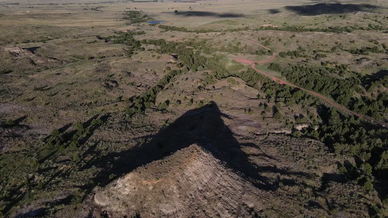 여름 저녁 와이오밍 주 웨스턴 힐스 휴양지 너머 정상과 오프로드 트레일에 초원이 있는 큰 언덕을 바라보며 비행