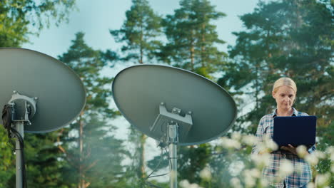 mujer sintoniza antenas parabólicas al aire libre utiliza tablet