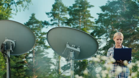 frau stellt satellitenschüsseln im freien ein und verwendet tablet