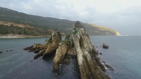 reverse aerial view showing the zoological reserve pedra da anicha (in the beauty arrabida natural park, portugal), with many seagulls and sea geeses