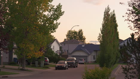 house at end of street in a suburban environment at dusk with cars in foreground.