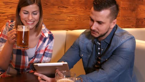 couple using digital tablet while having a glass of beer