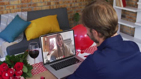 caucasian couple on a valentines date video call man waving to laughing woman on laptop screen