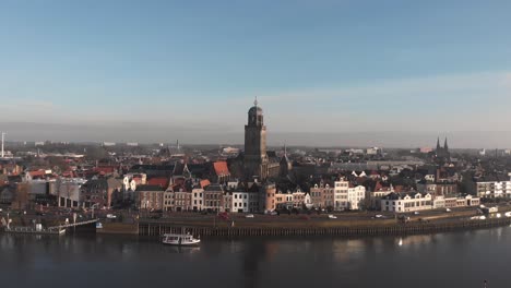 ferryboat in front of dutch hanseatic medieval city of deventer in the netherlands reflecting in the river ijssel the historic cityscape at sunrise