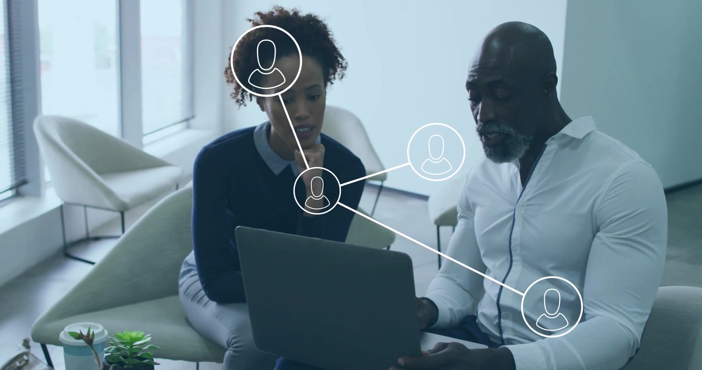 Colleagues opening laptop initiating network morphing circles into profiles for business meeting