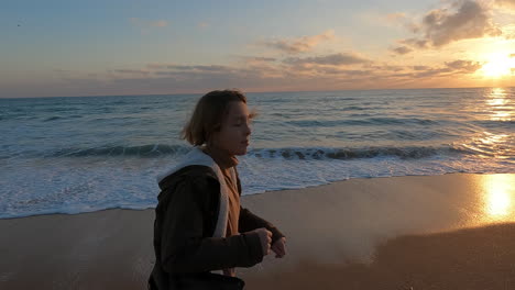 Teen-running-along-ocean-sunset-in-slowmo