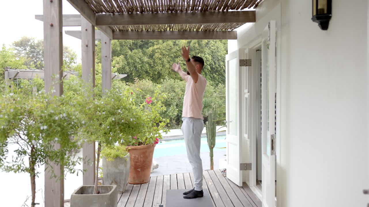 Practicing yoga, man stretching on yoga mat in outdoor patio area