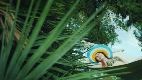 away from civilization a young woman relaxes on a hammock around the green palm trees the blue sky