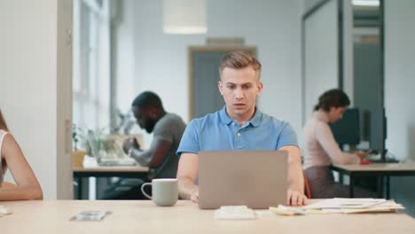 upset man looking at laptop computer at workplace. shocked man reading news