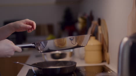 mujer freyendo panqueques en la sartén en la cocina y volviéndolos