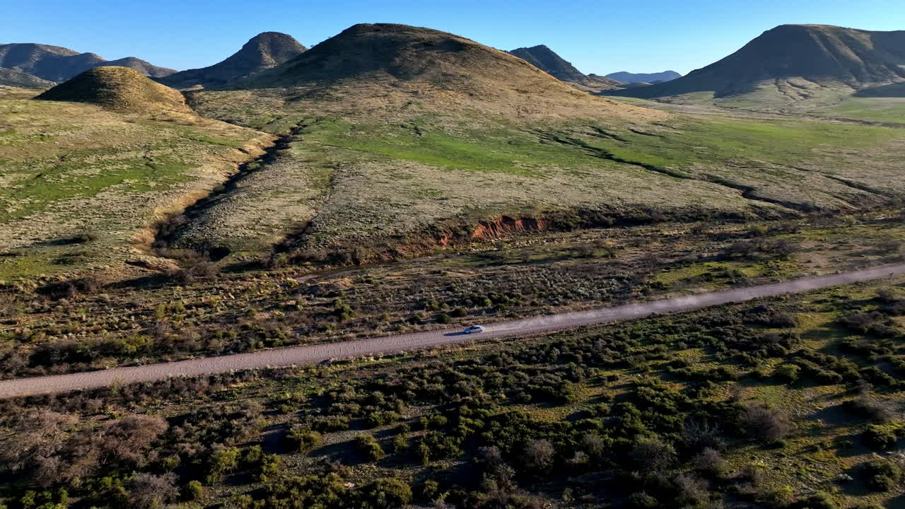 애리조나 주 윌스 (willcox) 의 길에서 운전하는 자동차의 공중 촬영, 배경에는 산과 차 뒤에 먼지가 있는 광면 추적 드론 촬영