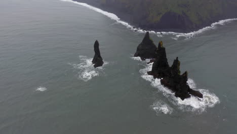 aerial: drone crane shot of reynisdrangar sea stacks in reynishjara black sand beach in iceland