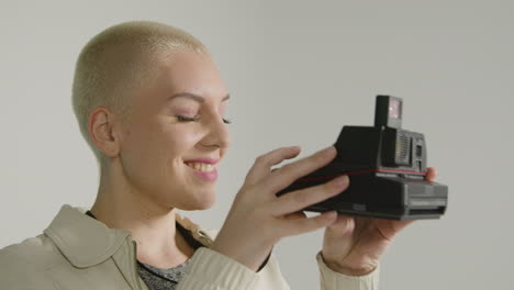 side view of a female photographer posing with instant film camera 02