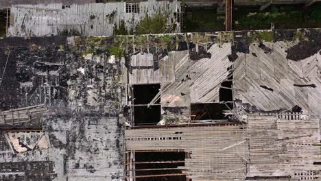 damaged roof of a building during military action. abandoned building with many holes outdoors. top aerial view. camera rising up.