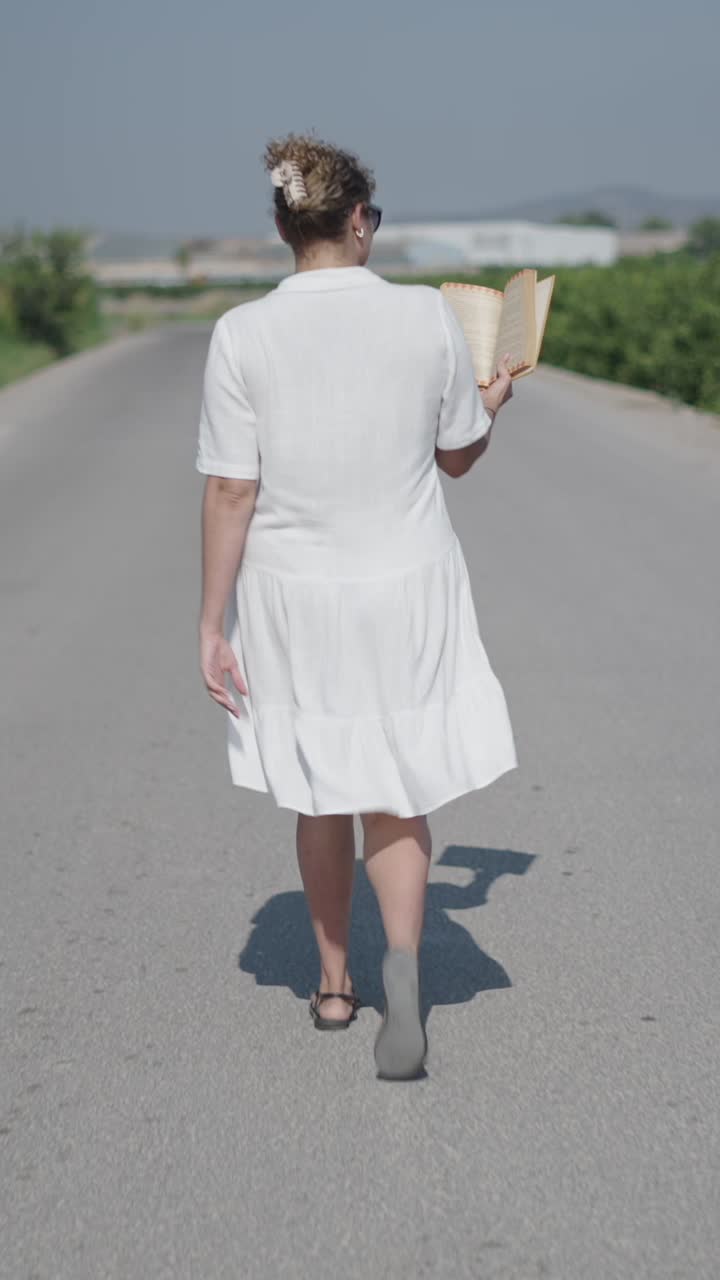 Donna che cammina per strada con un libro